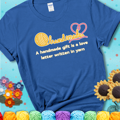 Soft script-style design with heart detail. Text reads: “A Handmade Gift Is a Love Letter Written in Yarn.” A sweet and sentimental shirt for crocheters who craft from the heart, showing a blue tee with a teal sunflower background