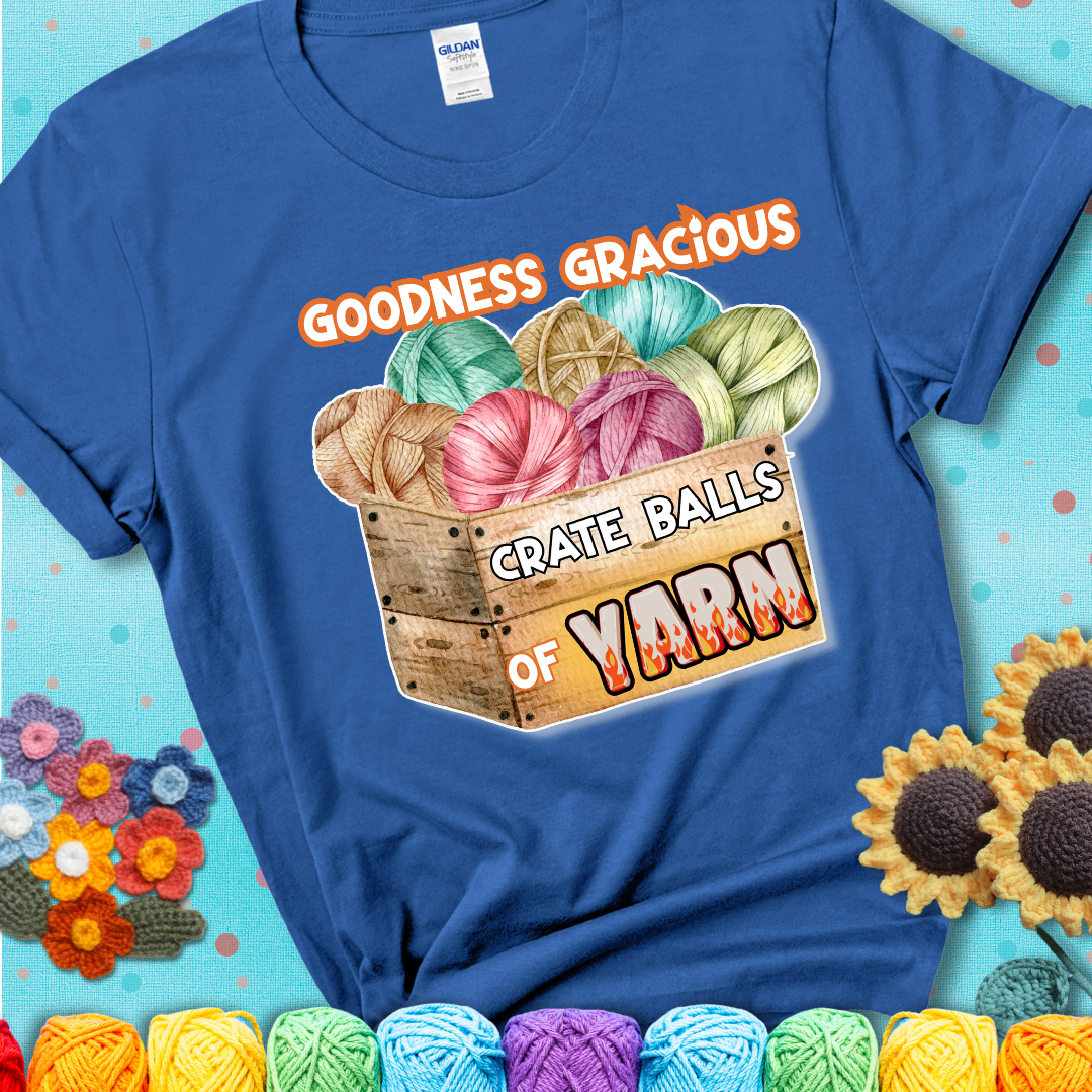 Wooden crate filled with colorful yarn balls and bold text “Goodness Gracious, Crate Balls of Yarn” with flame effects, a funny gift for crocheters showing a blue tee with a teal sunflower background