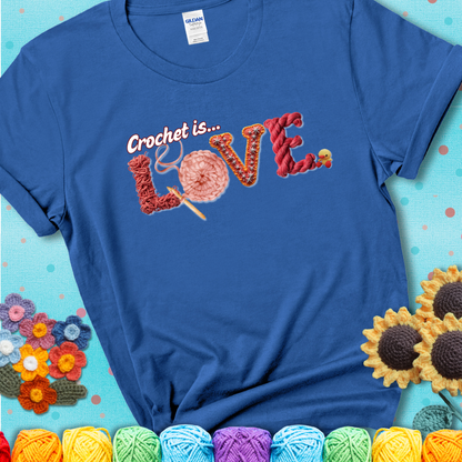 A blue t-shirt featuring the word "LOVE" spelled with different crochet textures and yarn in red tones, with the phrase “Crochet is…” above in script.