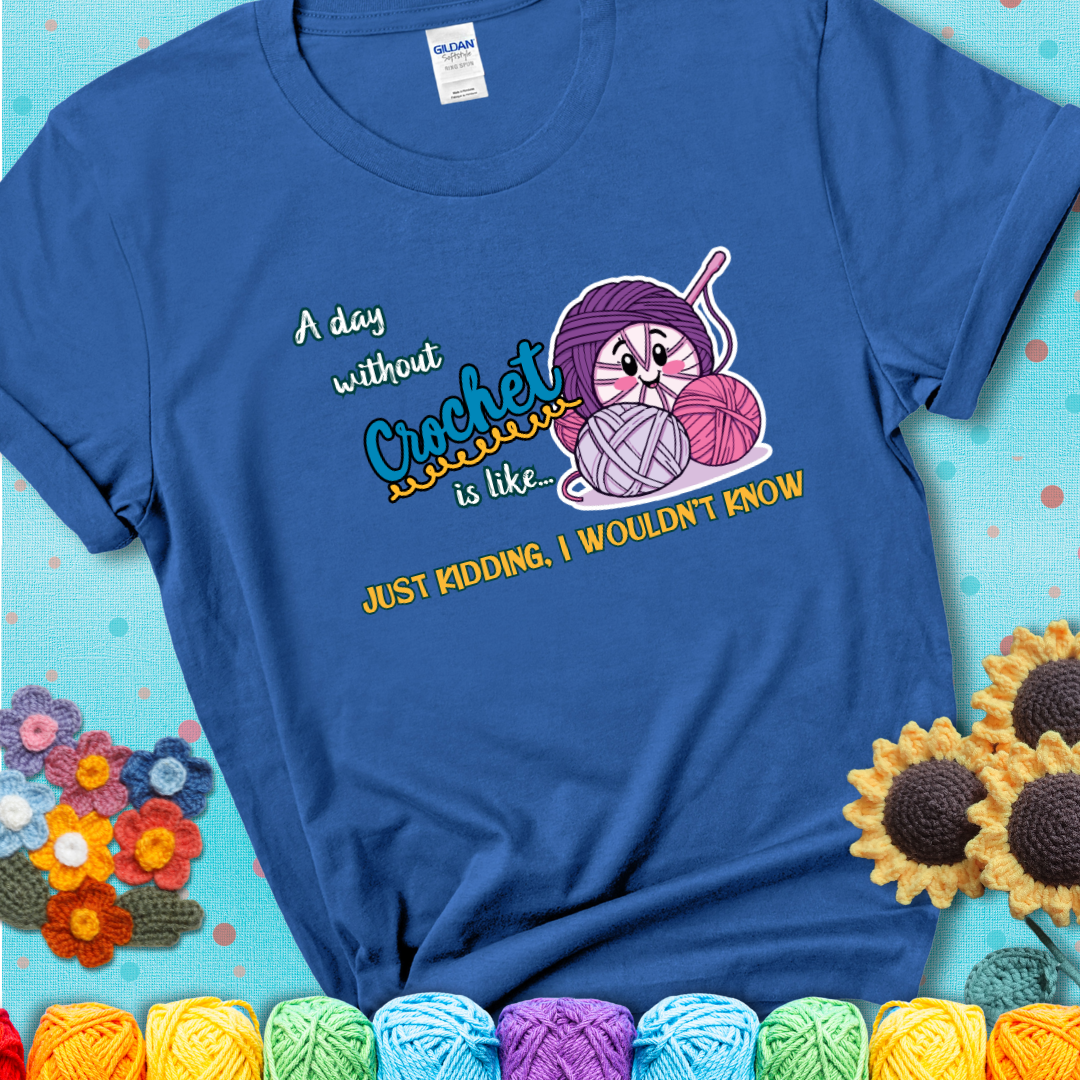 Blue t-shirt showing a smiling yarn ball character with text “A day without crochet is like... just kidding, I wouldn’t know”; funny crochet t-shirt.