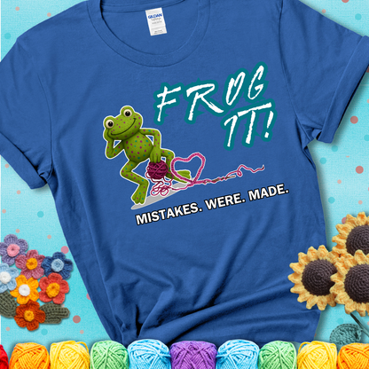 Green frog with yarn and heart-shaped loop. Text reads: “Frog It! Mistakes Were Made.” A playful crochet tee for anyone who's ever had to rip it back, showing a blue tee with a teal sunflower background