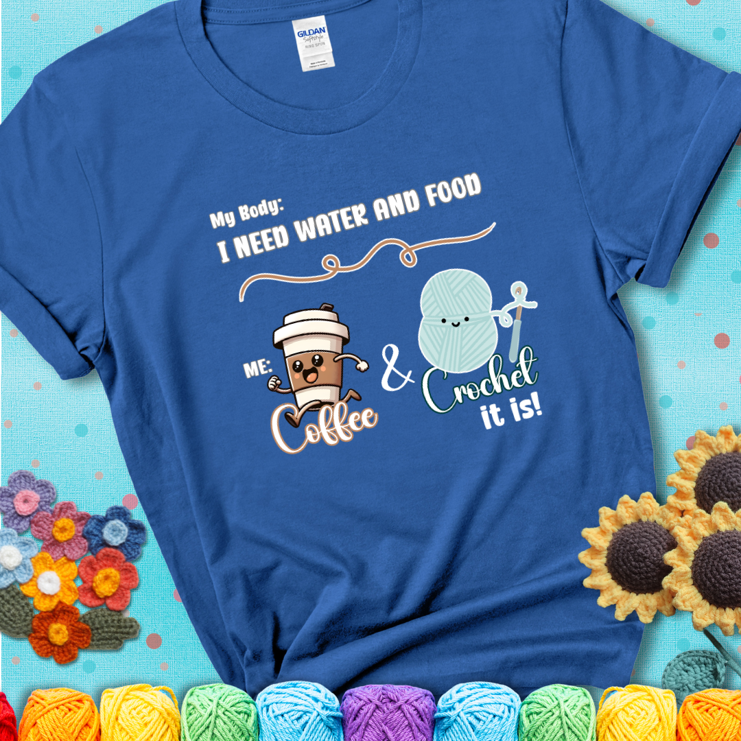Design reads “My body: I need water and food. Me: Coffee & Crochet it is,” with a smiling coffee cup and yarn ball characters on a blue t-shirt.