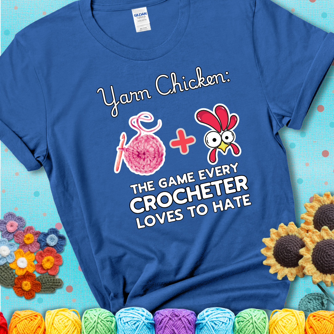 Cartoon chicken inside a yarn ball with crochet circle background. Text reads: “Yarn Chicken: The Game Every Crocheter Loves to Lose.” A fun and relatable tee for fiber artists who like to live on the edge, showing a blue tee with a teal sunflower background
