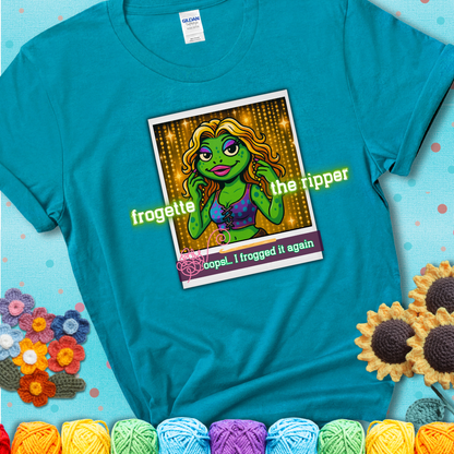Retro-styled illustration of a glamorous green frog in a sparkly outfit, labeled "Frogette the Ripper" with the phrase “Oops! I frogged it again” below, referencing both crochet and pop culture showing a blue-green teal tee with a teal sunflower background