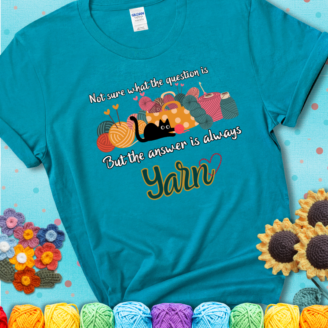 Tropical blue t-shirt with a black cat beside a basket of colorful yarn and the phrase, “Not Sure What The Question Was, But The Answer Is Yarn.”