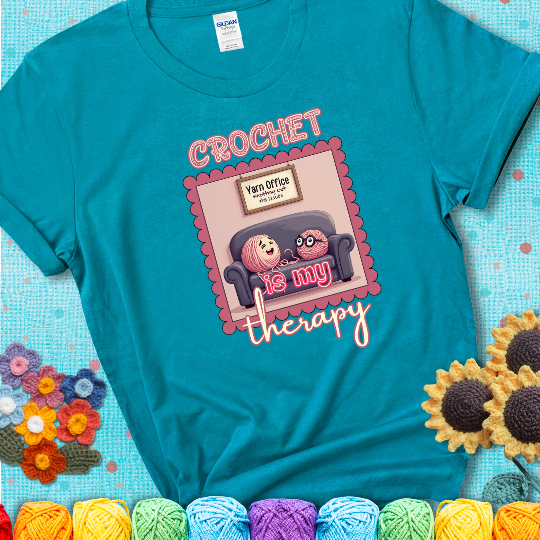 Teal t-shirt showing a simple text design with yarn cartoon figures. Text reads: “Crochet is My Therapy.” A calming tee for fiber lovers who find healing in every stitch.