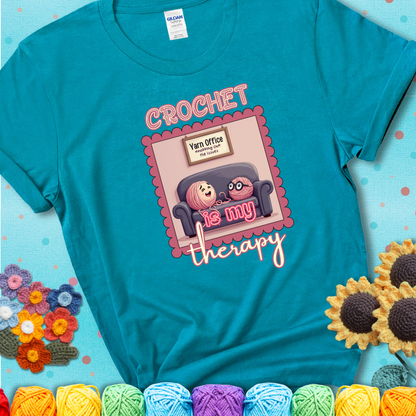 Teal t-shirt showing a simple text design with yarn cartoon figures. Text reads: “Crochet is My Therapy.” A calming tee for fiber lovers who find healing in every stitch.