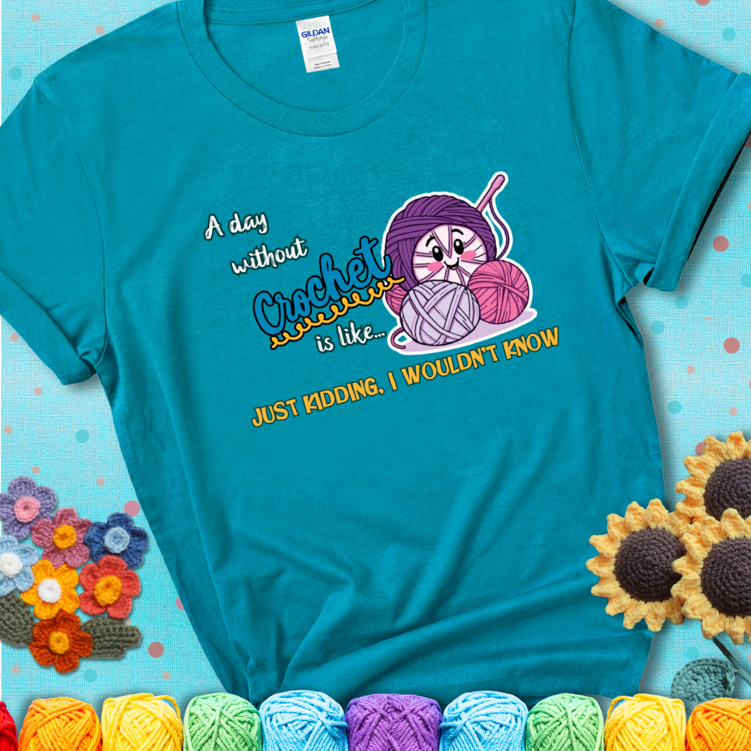 Teal t-shirt showing a smiling yarn ball character with text “A day without crochet is like... just kidding, I wouldn’t know”; funny crochet t-shirt.