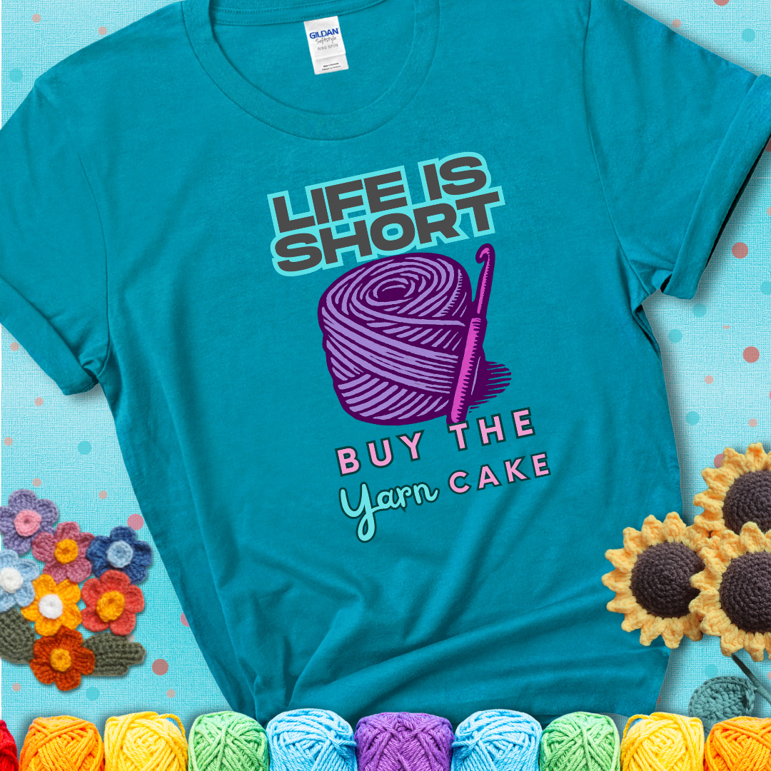 No regrets, just yarn. Design reads 'Life Is Short. Buy The Yarn (Cake)' , perfect crochet gift for yarn lovers, showing a blue-green teal tee with a teal sunflower background