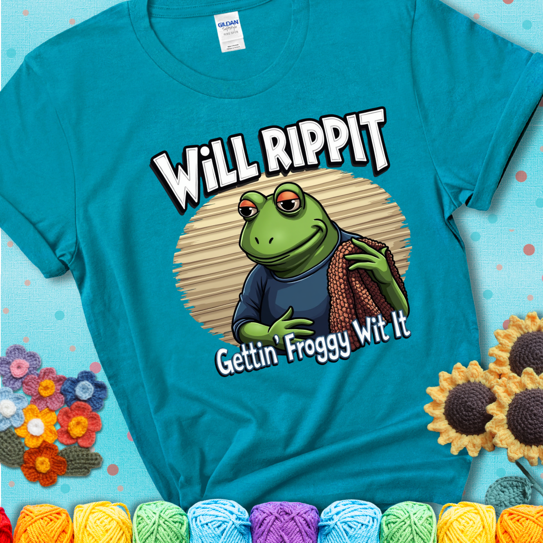 Cool frog holding a yarn blanket. Text reads: “Will Rippit Gettin’ Froggy Wit It.” A hip and humorous crochet blue-green teal tee for yarn lovers with rhythm.