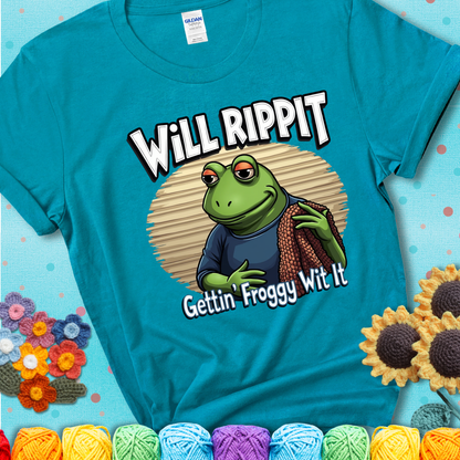 Cool frog holding a yarn blanket. Text reads: “Will Rippit Gettin’ Froggy Wit It.” A hip and humorous crochet blue-green teal tee for yarn lovers with rhythm.