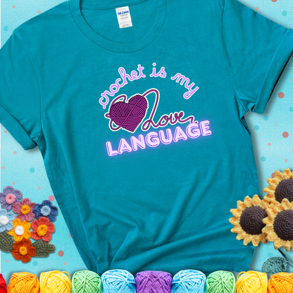 Say it with stitches Design reads 'Crochet Is My Love Language', perfect crochet gift for yarn lovers; showing a blue-green teal tee with a teal sunflower background