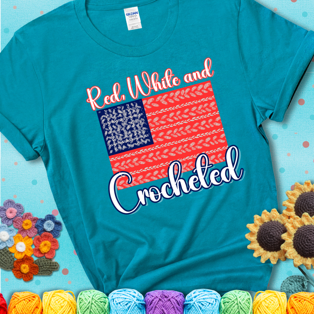 Teal t-shirt showing a patriotic crochet-themed American flag design with red and white yarn stitches forming the stripes and blue and white stitches as stars.
