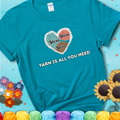 Tropical blue t-shirt with a colorful heart made of yarn textures and the phrase “Yarn Is All You Need” in retro lettering.