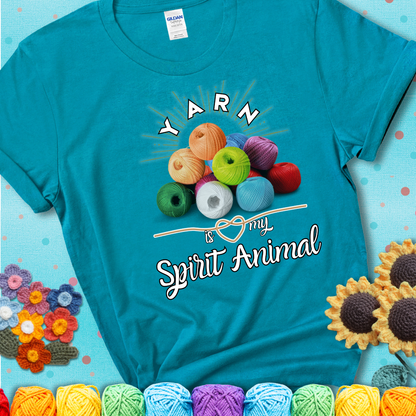 Stack of colorful yarn balls with radiant glow. Text reads: “Yarn Is My Spirit Animal.” A calming and colorful tee for fiber lovers who find zen in stitching, showing a blue-green teal tee with an aqua sunflower background