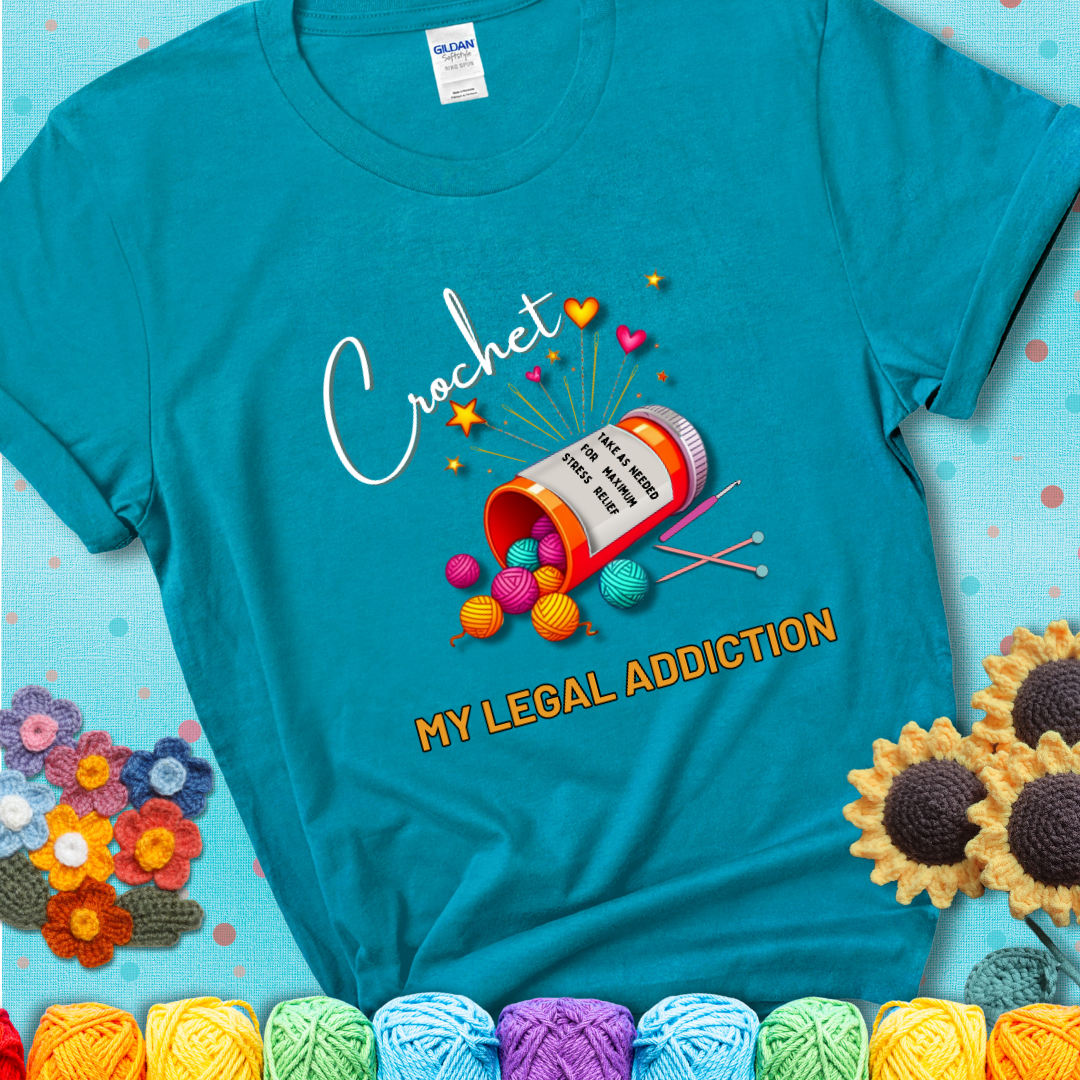 Tropical Blue t-shirt with a prescription bottle spilling colorful yarn balls, small crochet details, and the phrase “Crochet: My Legal Addiction.”