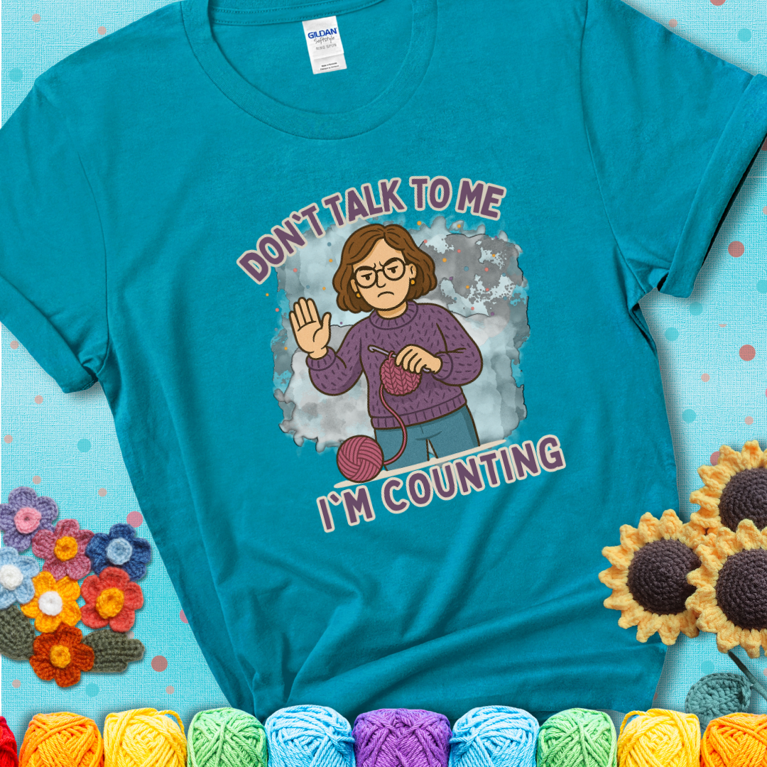 Tropical Blue t-shirt with an annoyed maker holding up a hand beside yarn, with the phrase “Don’t Talk To Me, I’m Counting.”