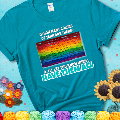 Teal t-shirt with rainbow skeins of yarn stacked in color gradient with playful question: “How many colors of yarn are there?” Answer: “I'll let you know when I have them all.”