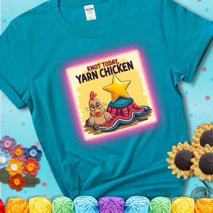 A teal t-shirt showing a frazzled cartoon chicken stands next to a nearly-finished project with minimal yarn left, with the phrase “Knot Today, Yarn Chicken” above.