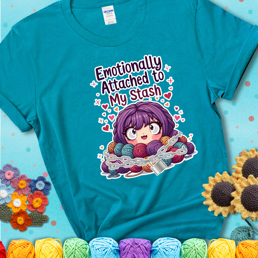 Adorable character with wide eyes hugging a yarn stash wrapped in chains and a lock, with the text “Emotionally Attached to My Stash”  on a blue-green teal tee.