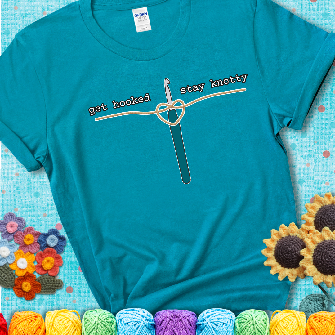 Hooked on yarn? Same Design reads 'Get Hooked, Stay Knotty' , perfect crochet gift for yarn lovers, showing a blue-green teal tee with a teal sunflower background