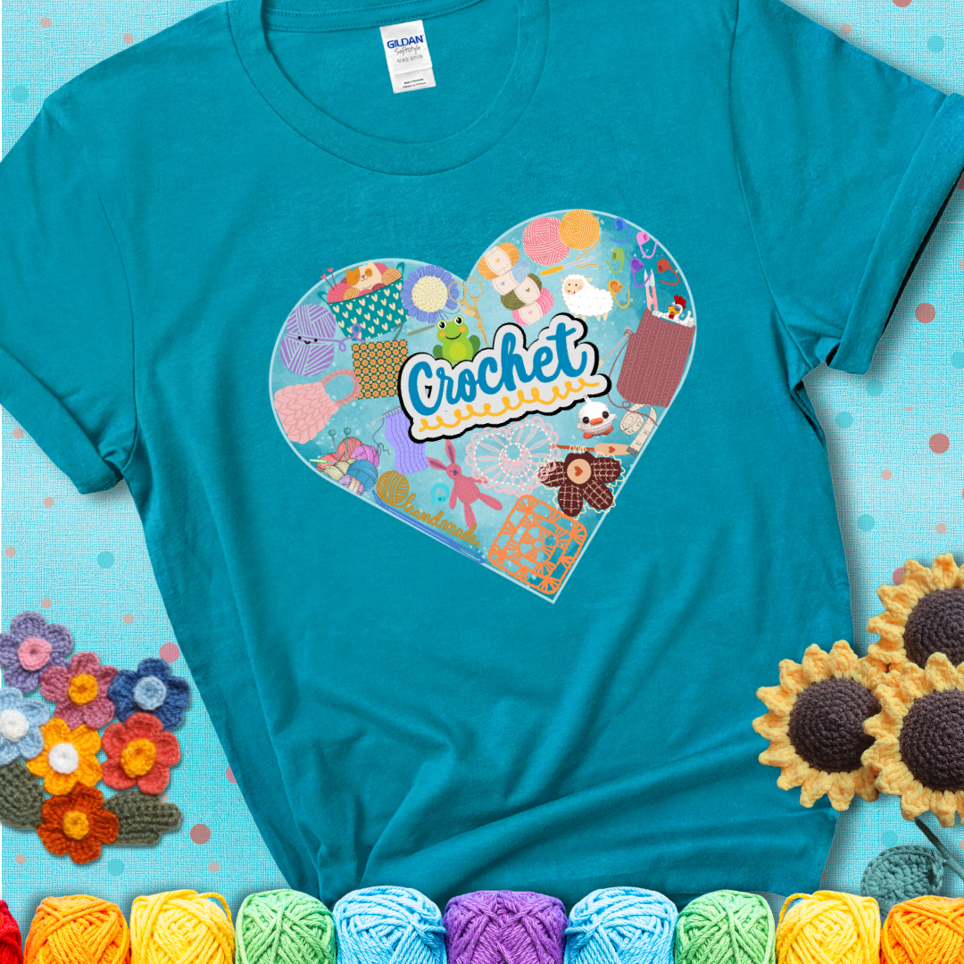 A heart filled with colorful crochet essentials including yarn, hooks, scissors, notions, and handmade items, with the word "Crochet" prominently in the center of a teal t-shirt.