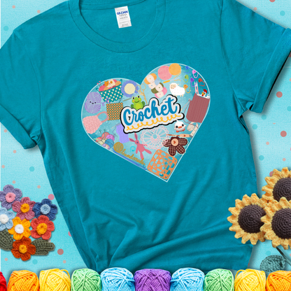 A heart filled with colorful crochet essentials including yarn, hooks, scissors, notions, and handmade items, with the word "Crochet" prominently in the center of a teal t-shirt.
