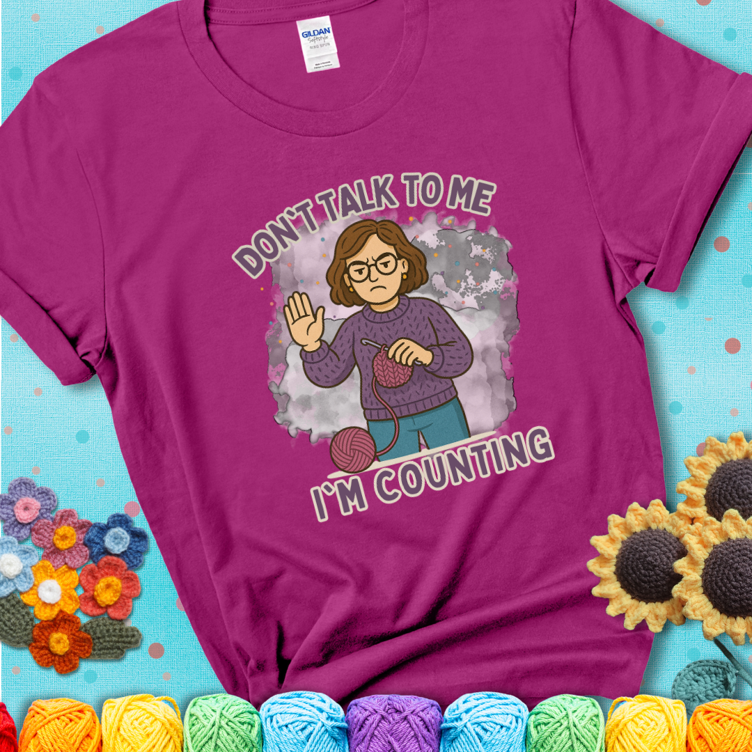 Antique Heliconia t-shirt with an annoyed maker holding up a hand beside yarn, with the phrase “Don’t Talk To Me, I’m Counting.”