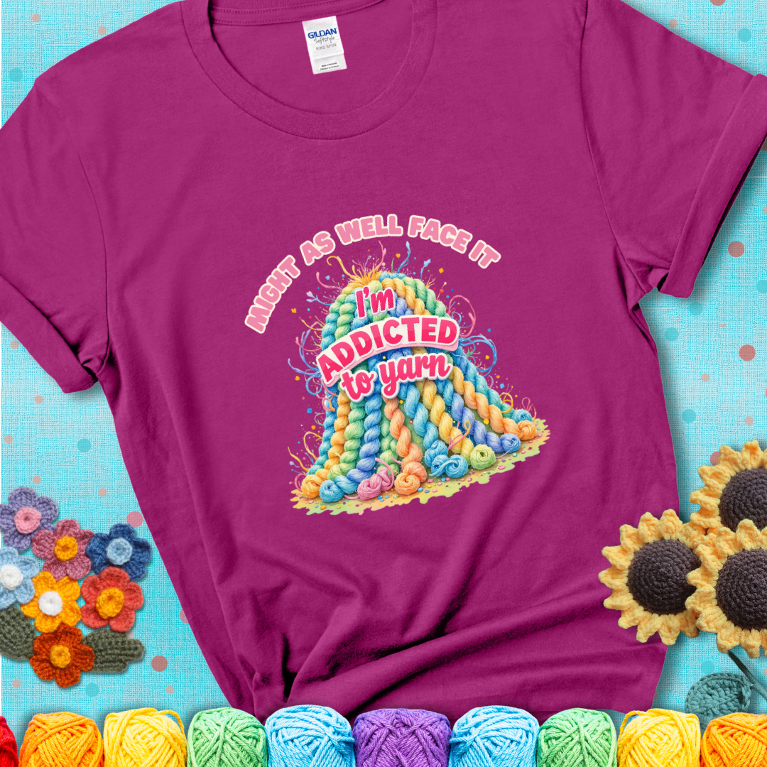Antique Heliconia t-shirt with a colorful mountain of pastel yarn hanks and the phrase “Might As Well Face It, I’m Addicted To Yarn” in pink and red lettering.