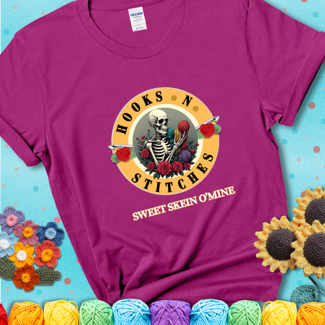 Antique Heliconia t-shirt with a skeleton holding colorful yarn, roses, crochet hooks, and the phrases “Hooks ’N Stitches” and “Sweet Skein O’Mine.”