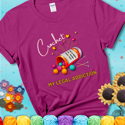 Antique Heliconia t-shirt with a prescription bottle spilling colorful yarn balls, small crochet details, and the phrase “Crochet: My Legal Addiction.”