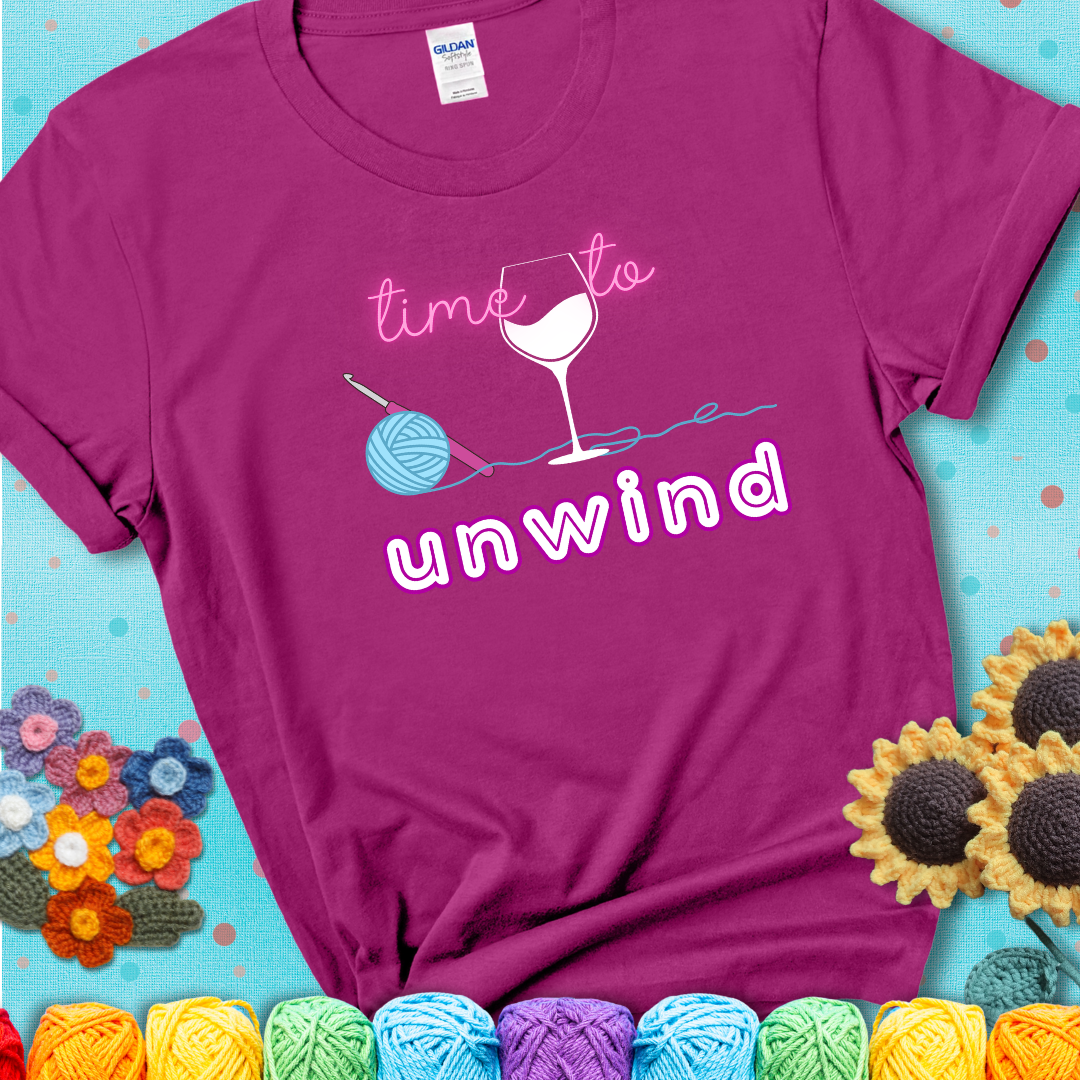 Wine down with your yarn out Design reads 'Time To Unwind' , perfect crochet gift for yarn lovers showing a magenta tee with a teal sunflower background