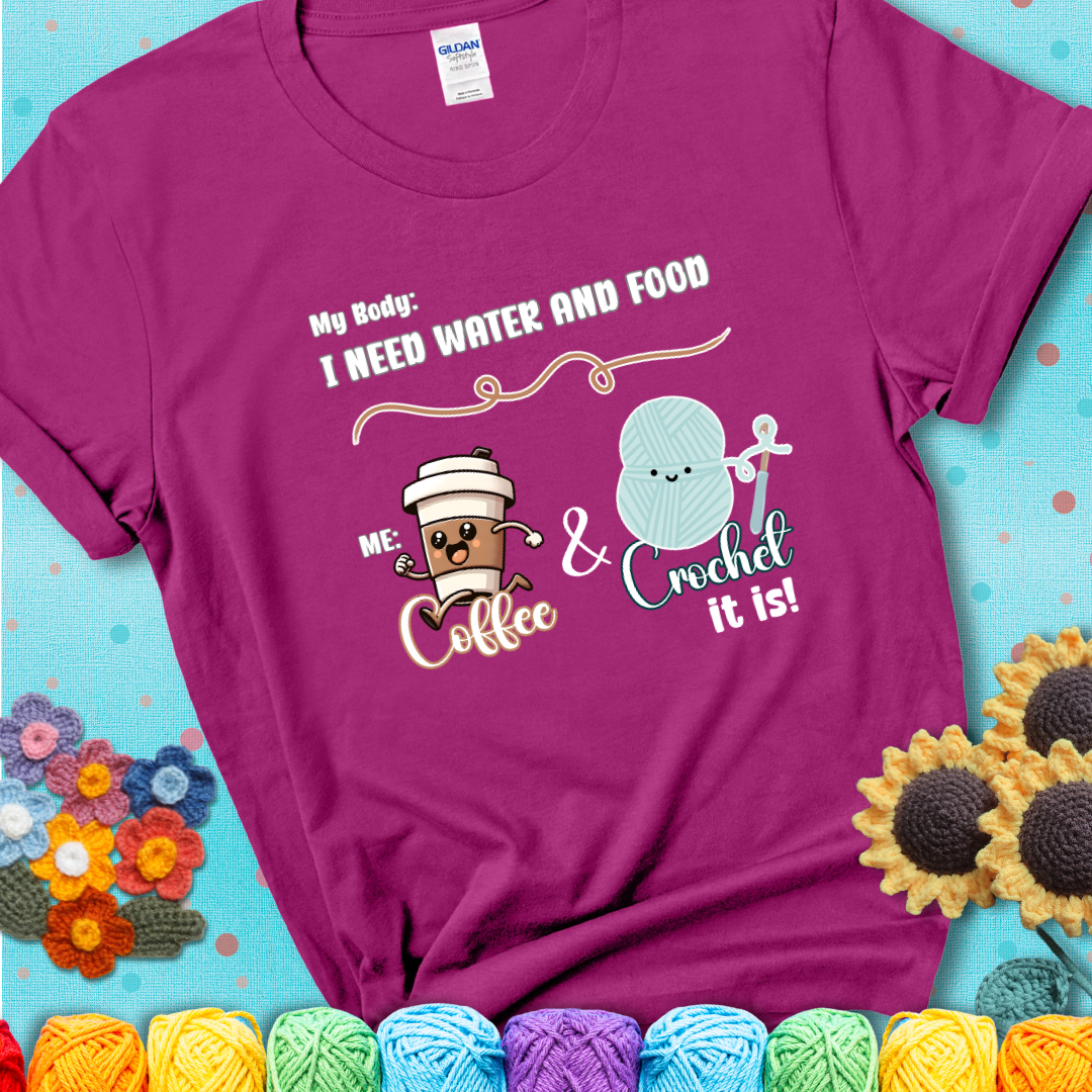 Design reads “My body: I need water and food. Me: Coffee & Crochet it is,” with a smiling coffee cup and yarn ball characters on a magenta t-shirt.
