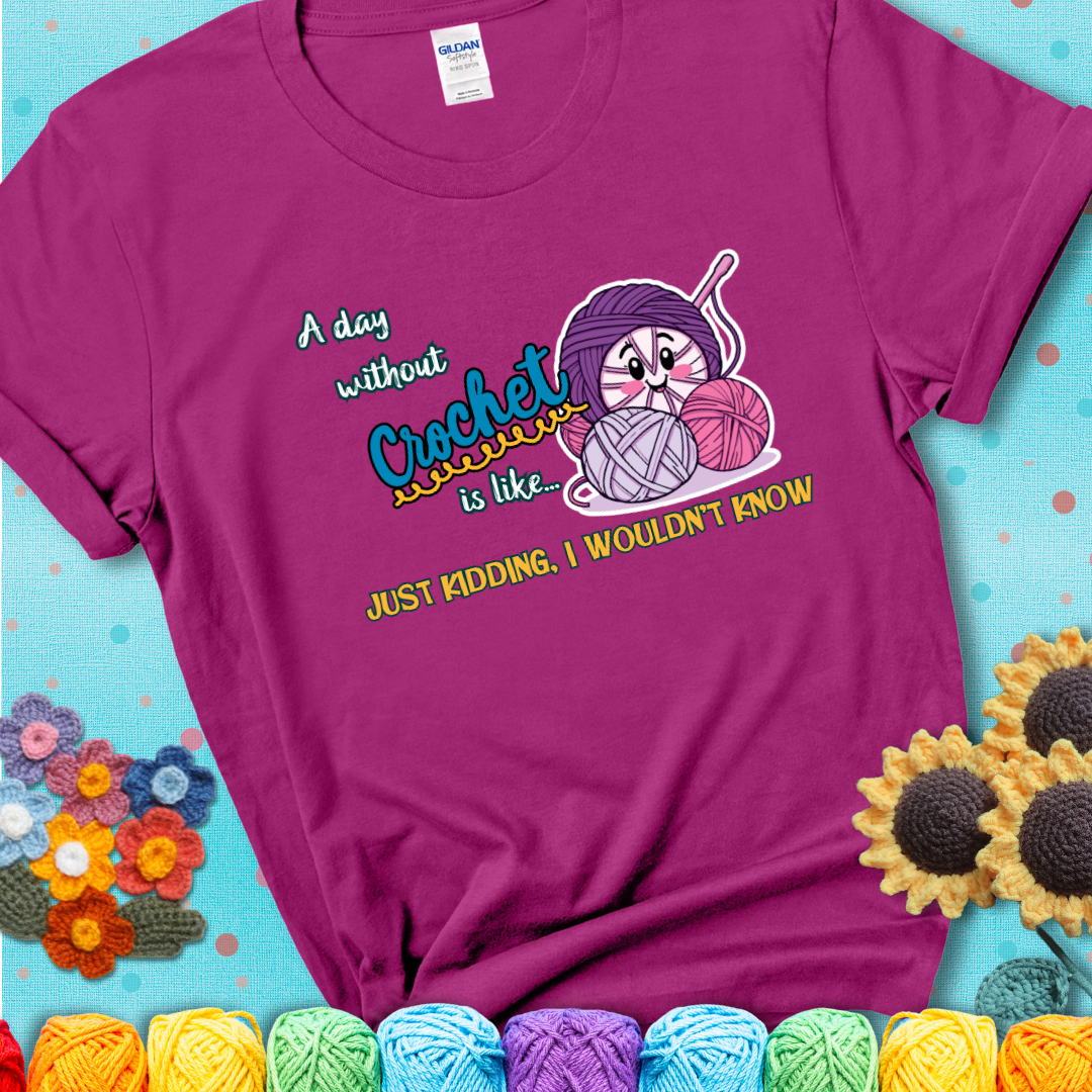 Magenta t-shirt showing a smiling yarn ball character with text “A day without crochet is like... just kidding, I wouldn’t know”; funny crochet t-shirt.