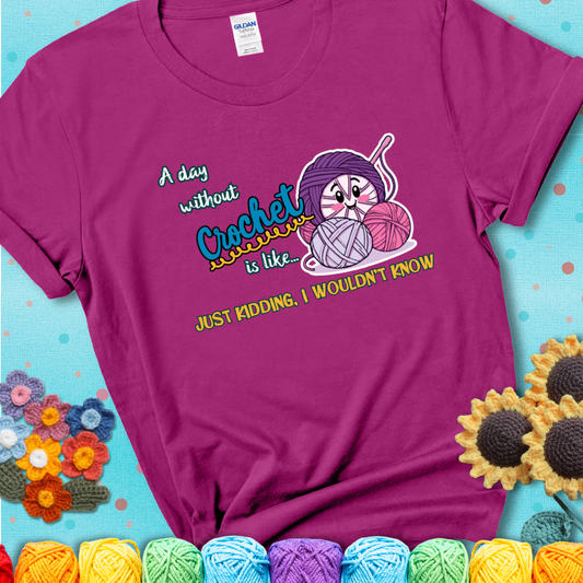Magenta t-shirt showing a smiling yarn ball character with text “A day without crochet is like... just kidding, I wouldn’t know”; funny crochet t-shirt.