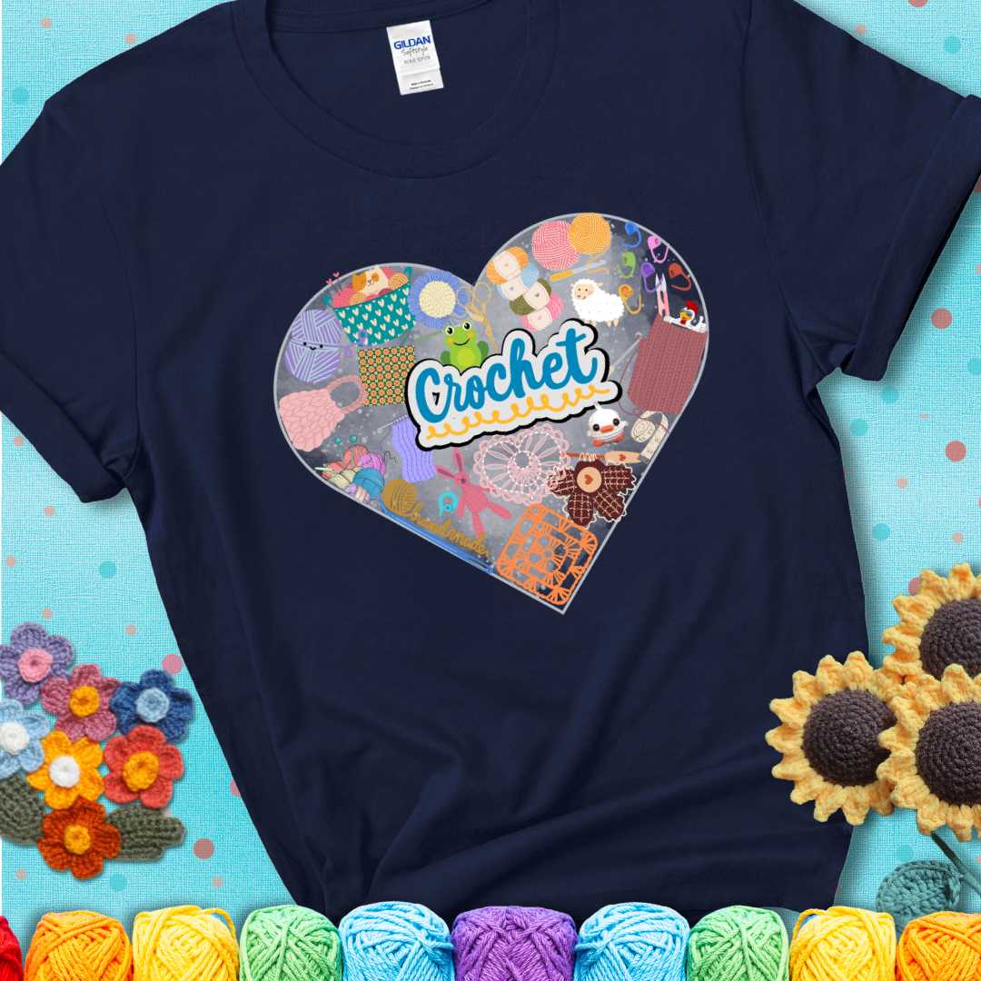 A heart filled with colorful crochet essentials including yarn, hooks, scissors, notions, and handmade items, with the word "Crochet" prominently in the center of a navy blue t-shirt.