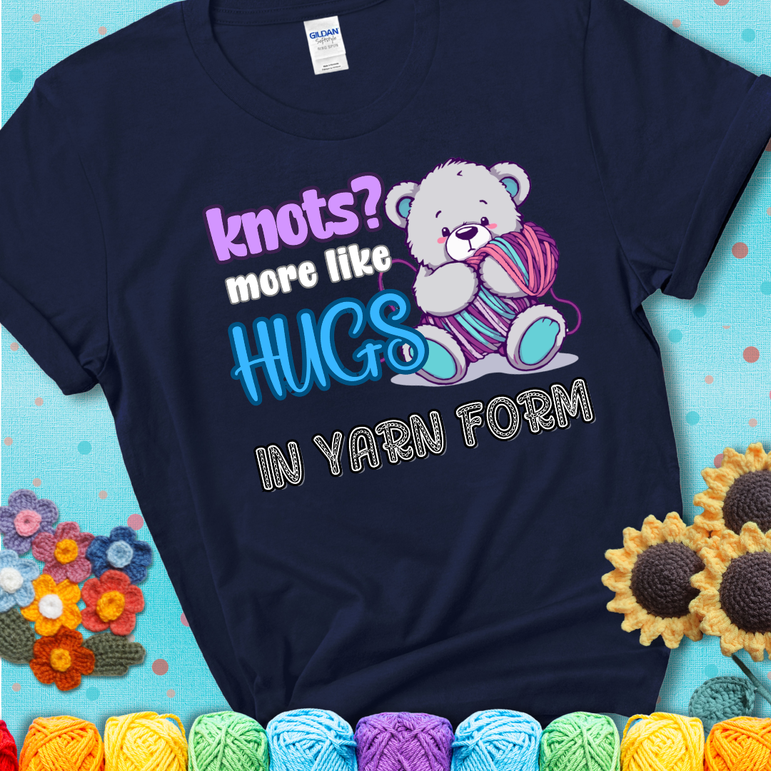 Cute teddy bear holding colorful yarn ball with hearts. Text reads: “Knots? More Like Hugs in Yarn Form.” Perfect for cozy gift-givers and yarn lovers, showing a navy blue tee with a teal sunflower background