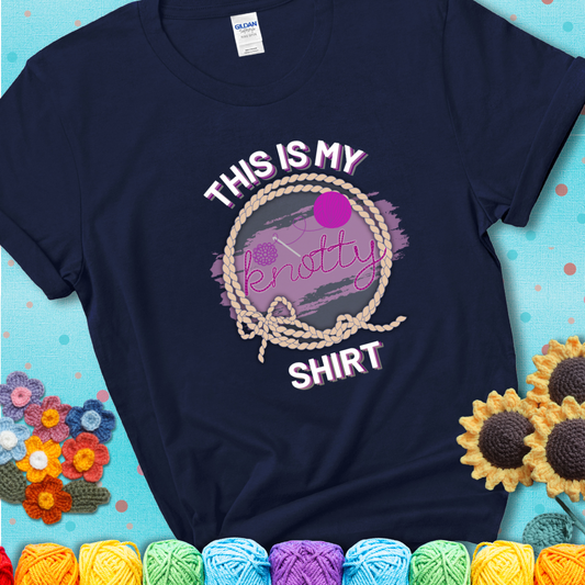 Navy t-shirt with the phrase “This is My Knotty Shirt” inside a rope circle, featuring a yarn ball and crochet hook forming the word “knotty.”
