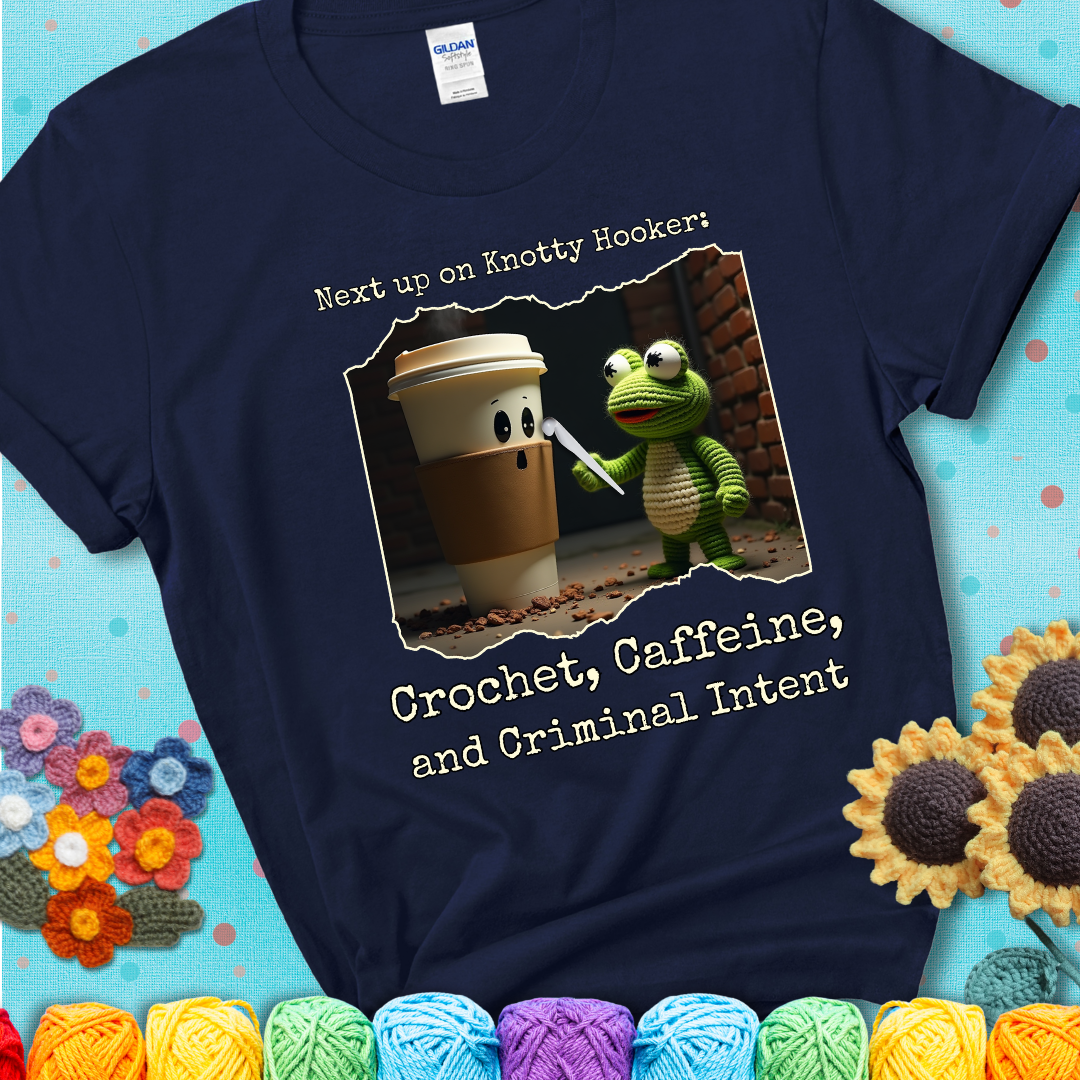 A crocheted frog holding a crochet hook confronts a surprised coffee cup in a dim alleyway with text: "Next up on Knotty Hooker: Crochet, Caffeine, and Criminal Intent," showing a navy blue tee with a teal sunflower background