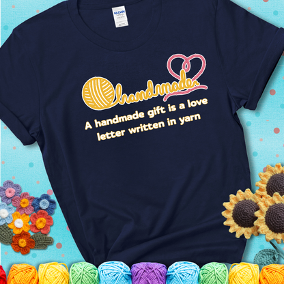 Soft script-style design with heart detail. Text reads: “A Handmade Gift Is a Love Letter Written in Yarn.” A sweet and sentimental shirt for crocheters who craft from the heart, showing a navy blue tee with a teal sunflower background