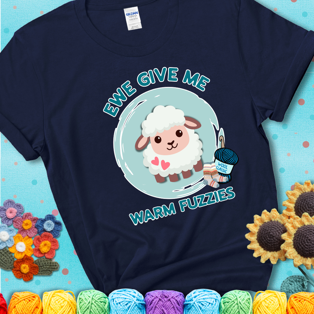 Navy blue t-shirt showing a cartoon sheep with pink hearts, wool socks, and yarn labeled “Wool Classic.” Text reads “Ewe Give Me Warm Fuzzies.”