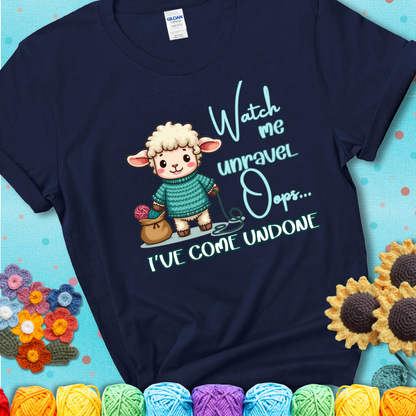 Navy blue t-shirt with a cute sheep holding yarn looks startled with the phrase “Watch me unravel… Oops, I’ve come undone.” Perfect mix of whimsy and yarn life chaos.
