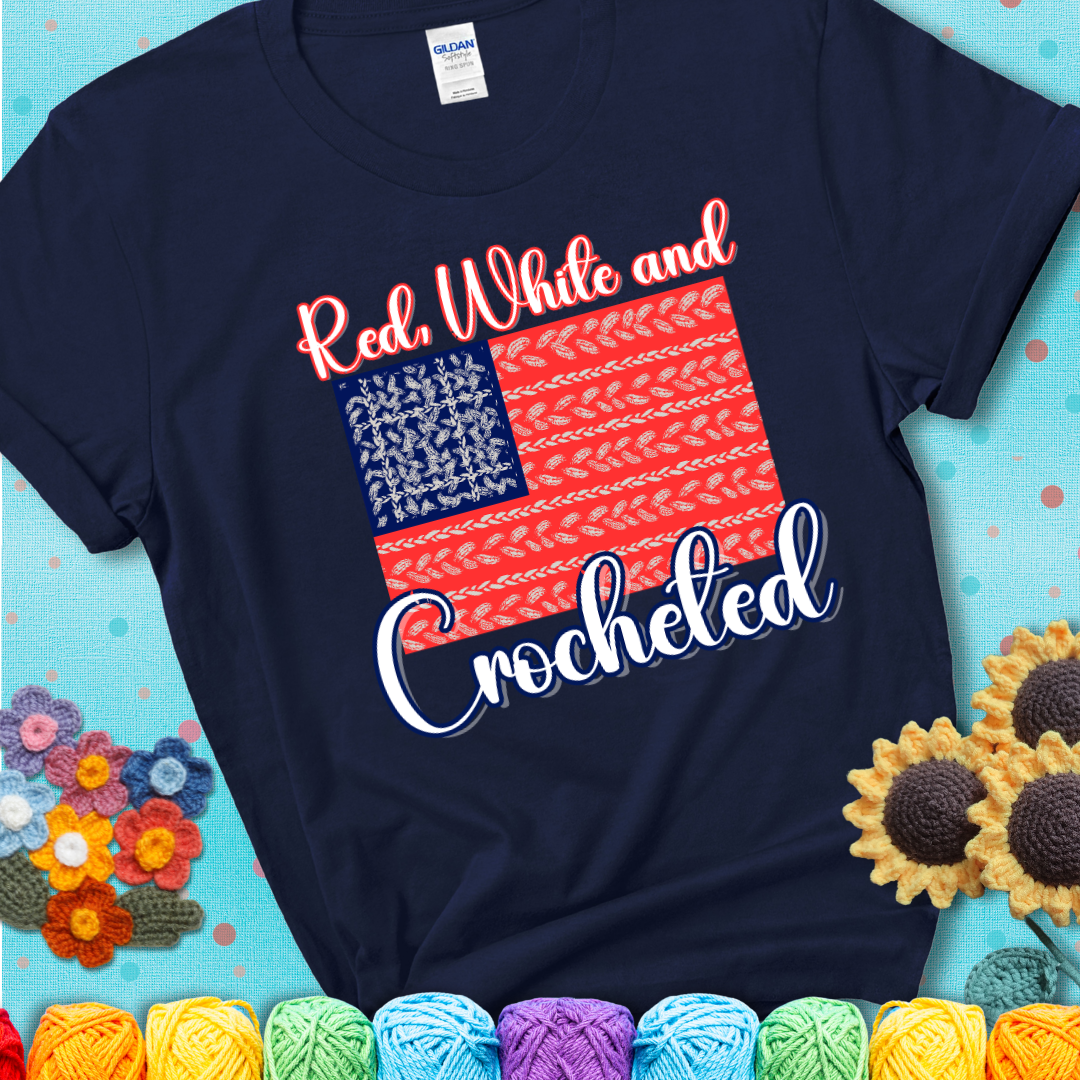 Navy blue t-shirt showing a patriotic crochet-themed American flag design with red and white yarn stitches forming the stripes and blue and white stitches as stars.