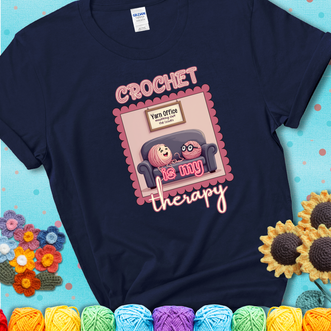 Navy blue t-shirt showing a simple text design with yarn cartoon figures. Text reads: “Crochet is My Therapy.” A calming tee for fiber lovers who find healing in every stitch.