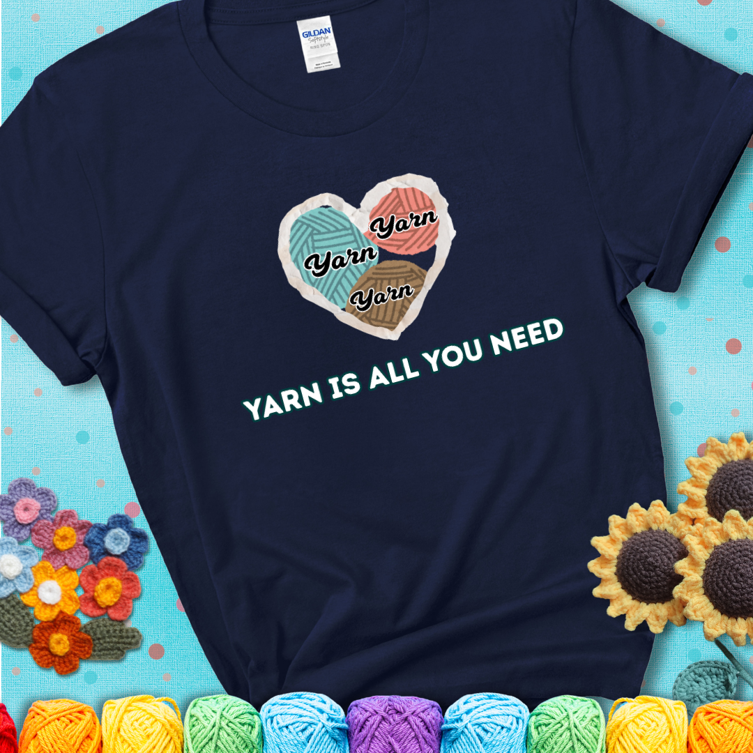 Navy t-shirt with a colorful heart made of yarn textures and the phrase “Yarn Is All You Need” in retro lettering.