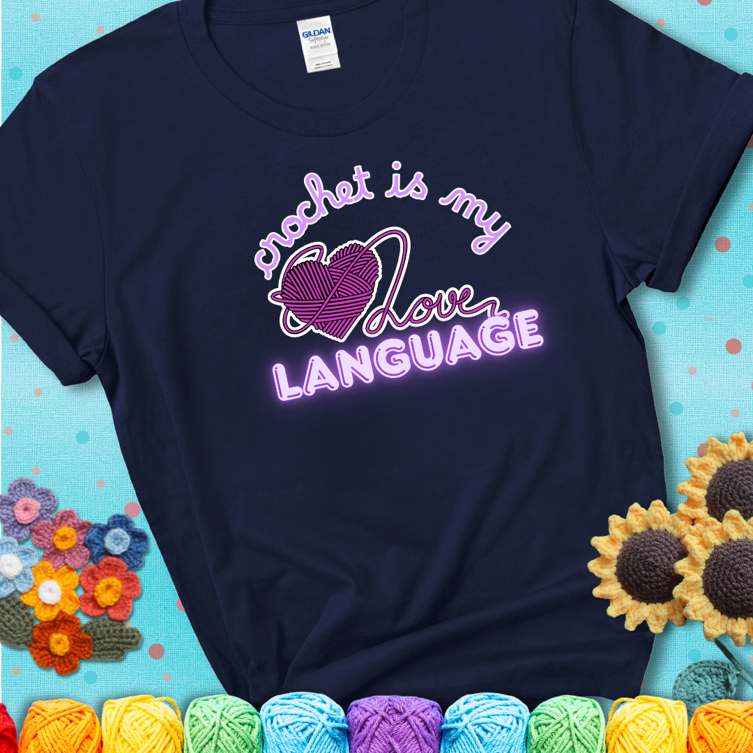 Say it with stitches Design reads 'Crochet Is My Love Language', perfect crochet gift for yarn lovers; showing a navy blue tee with a teal sunflower background