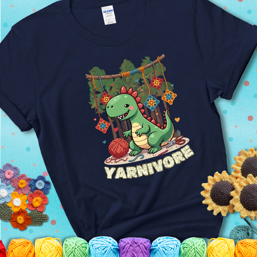 Navy blue t-shirt shows a cute green dinosaur with yarn ball and granny squares, text “Yarnivore”, a fun crochet shirt for dino and yarn fans.
