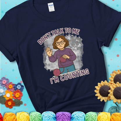 Navy t-shirt with an annoyed maker holding up a hand beside yarn, with the phrase “Don’t Talk To Me, I’m Counting.”