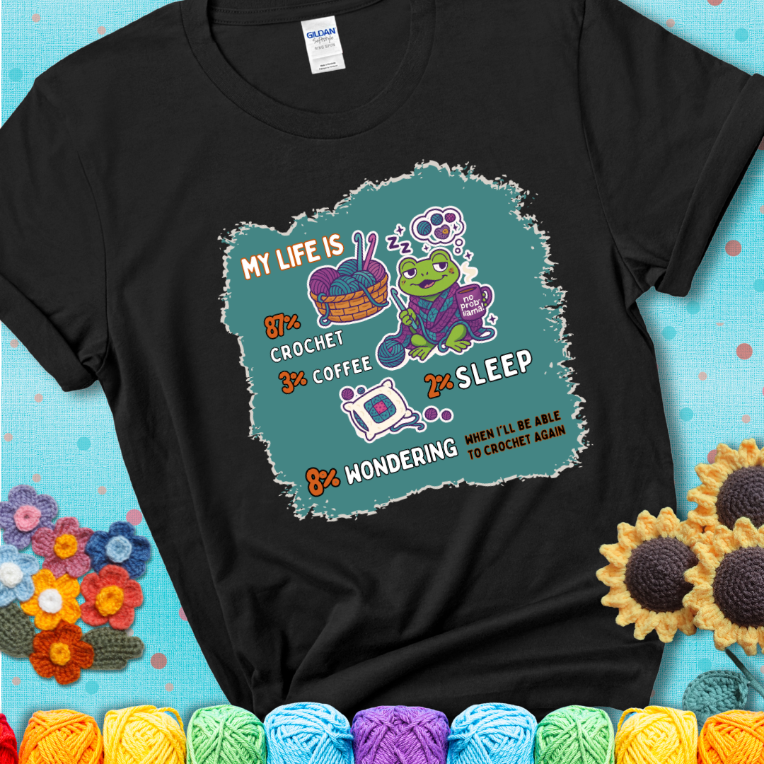 Black t-shirt with a crocheting frog, coffee, yarn, and text showing a playful life breakdown: 87% crochet, 3% coffee, 2% sleep, 8% wondering when to crochet again.
