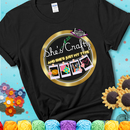 Text on black tee reads "She’s Crafty & She’s Just My Type" with yarn, fabric, painting, and cross-stitch icons hanging like Polaroids